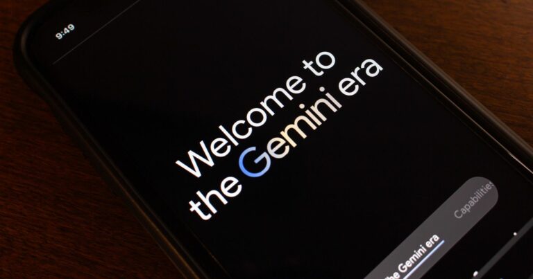 Imagem de um smartphone exibindo a mensagem "Welcome to the Gemini era" na tela. A palavra "Gemini" destaca-se com a letra "G" em azul, remetendo à identidade visual do Google. O dispositivo está sobre uma superfície de madeira, e a tela tem fundo preto com texto em branco, conferindo um design moderno e minimalista