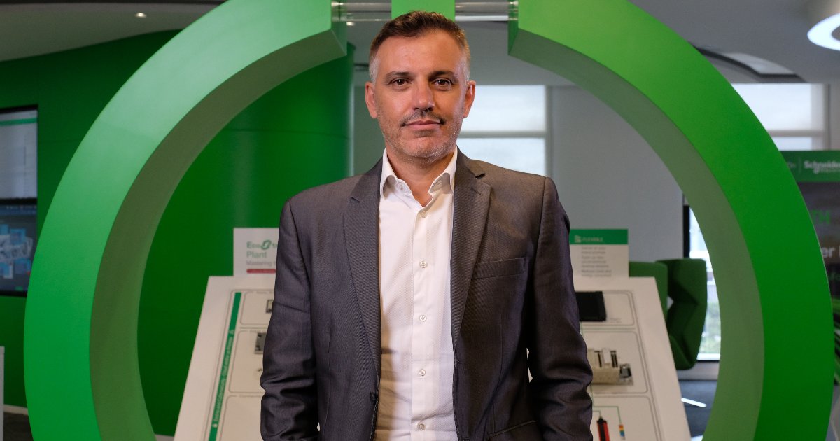 Roberto Rossi, presidente da Schneider Electric para o Brasil, posando em frente a uma estrutura verde no ambiente corporativo da empresa