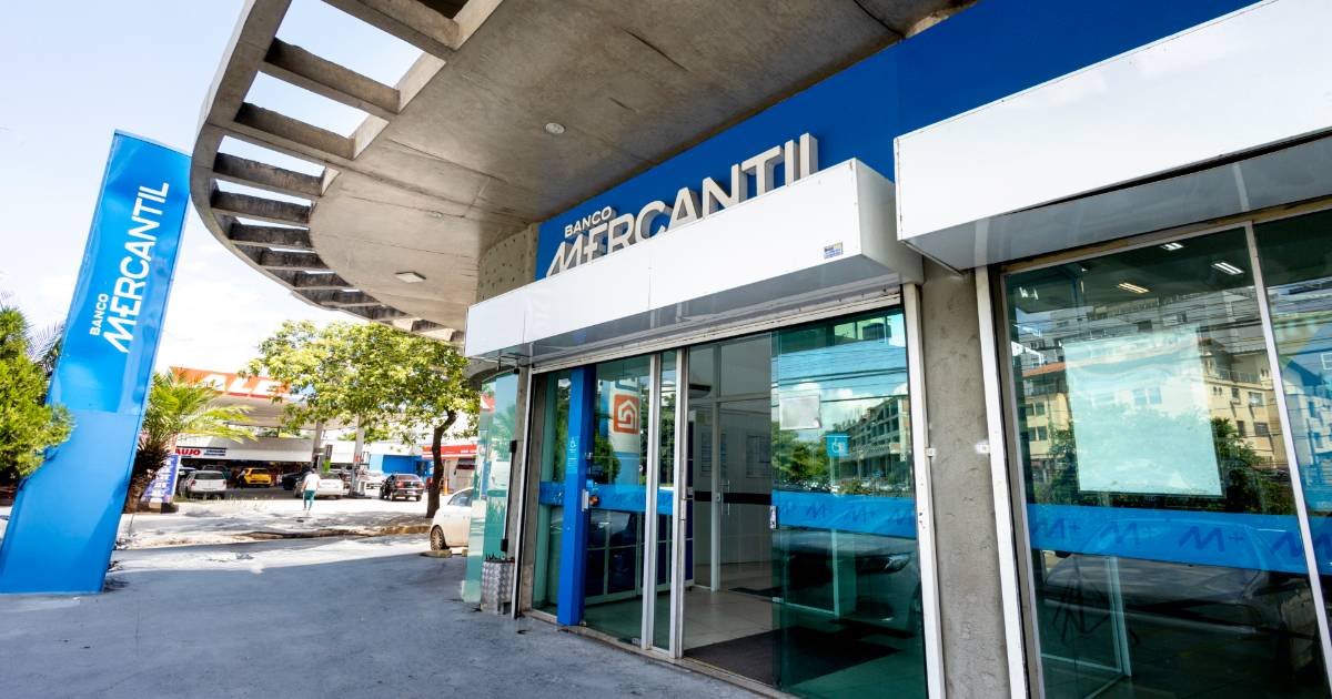 Fachada moderna de uma agência do Banco Mercantil, destacando a entrada com portas de vidro e a identidade visual azul e branca da instituição (google cloud)