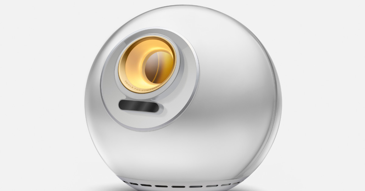 Dispositivo em formato esférico conhecido como "Orb", utilizado para escaneamento de íris, desenvolvido pela empresa Tools for Humanity, fundada por Sam Altman. O design moderno apresenta uma superfície metálica prateada, com um detalhe circular dourado no centro, onde ocorre o escaneamento. O fundo da imagem é branco, destacando a aparência futurista do dispositivo.