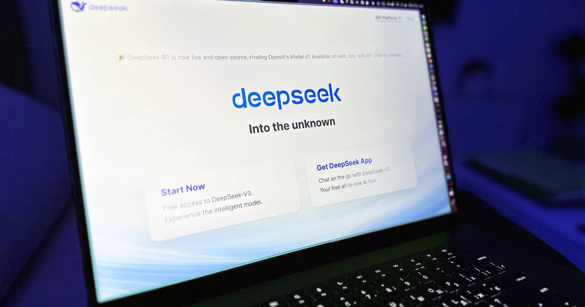 Imagem de um laptop com a tela mostrando a interface da DeepSeek. O título 'DeepSeek' aparece em destaque com o subtítulo 'Into the unknown' logo abaixo, em um fundo branco com tons suaves de azul. Há botões na interface com as opções 'Start Now' e 'Get DeepSeek App', incentivando o uso gratuito e o download do aplicativo. O ambiente ao redor está escuro, criando contraste com a tela iluminada (Europa)