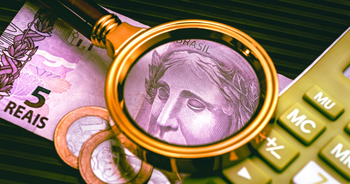A imagem mostra uma lupa ampliando o rosto da efígie da República presente em uma cédula de 5 reais do Brasil. Ao redor, há moedas de real e uma calculadora, simbolizando análise financeira, taxa de juros e economia. O uso da lupa sugere uma investigação detalhada sobre dinheiro, possivelmente em relação a inflação, juros ou finanças pessoais (juros, dinheiro, real, taxa de juros, lupa, dinheiro)