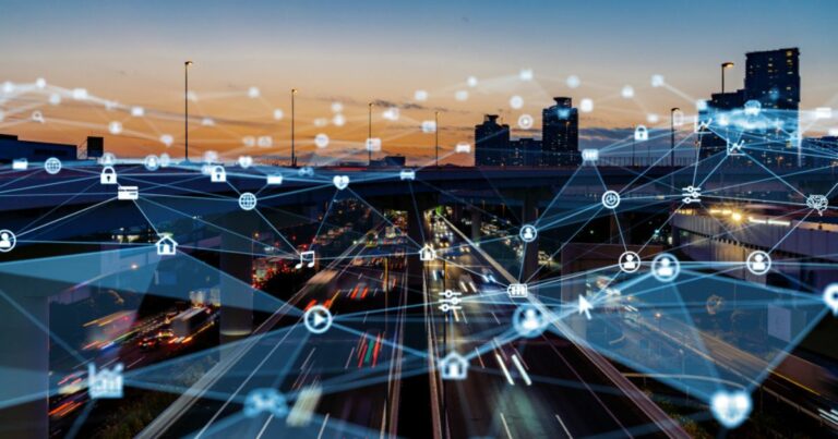 Imagem de uma cidade inteligente ao entardecer, com rodovias movimentadas e prédios modernos ao fundo. Sobre a cena urbana, há uma sobreposição de elementos gráficos representando conexões digitais e a infraestrutura de edge computing. Ícones de dispositivos conectados, como nuvem, cadeados, casas e globos, estão interligados por linhas, simbolizando a descentralização do processamento de dados na borda da rede. A composição visual reforça o conceito de conectividade avançada e Internet das Coisas (IoT) em um ambiente urbano digitalizado.
