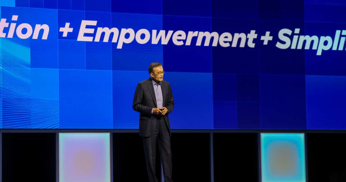 Lip-Bu Tan, novo CEO da Intel, durante a abertura do Intel Vision 2025. Ele está em pé no palco, vestindo terno escuro e camisa azul, com um grande telão ao fundo