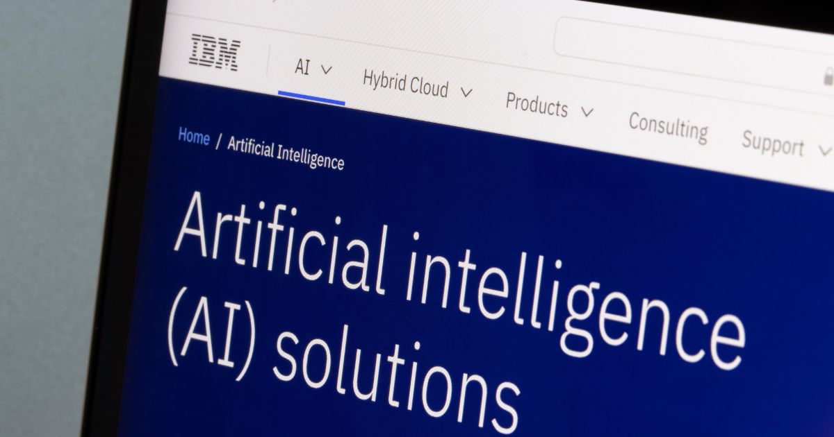 Imagem de um ecrã de computador exibindo o site da IBM, especificamente na secção de soluções de Inteligência Artificial (AI). O fundo é azul escuro com texto branco a dizer 'Artificial intelligence (AI) solutions'. A barra de navegação no topo apresenta categorias como AI, Hybrid Cloud, Products, Consulting e Support.