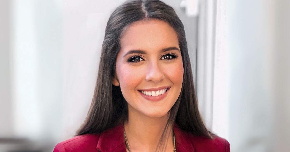 Renata Koch Alvarenga, fundadora da EmpoderaClima, aparece sorrindo em um retrato profissional. Ela está com os cabelos soltos e lisos, veste um blazer vermelho e está diante de um fundo neutro e claro, que destaca seu rosto (líder)