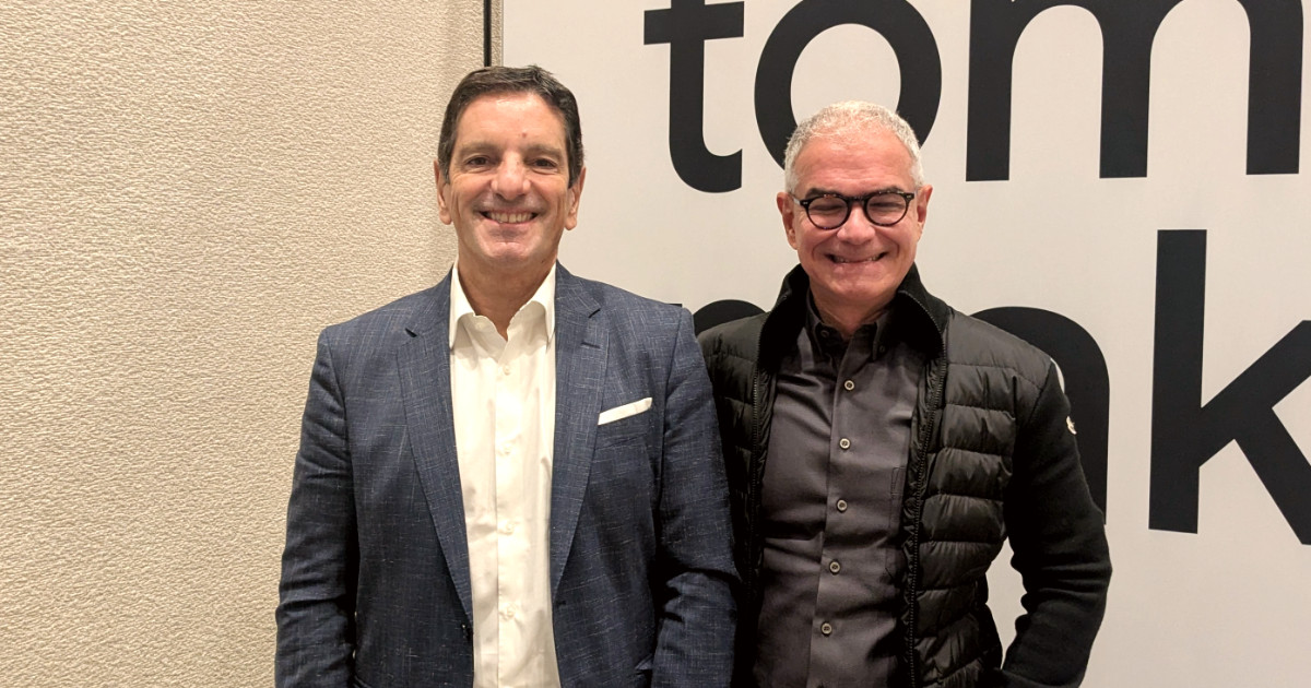 Ricardo Fernandes, presidente do Google Cloud para a América Latina, e Eduardo Lopes, head do Google Cloud Brasil, posam sorridentes lado a lado. Ricardo Fernandes veste paletó azul e camisa branca, enquanto Eduardo Lopes usa óculos, camisa escura e jaqueta preta. Ao fundo, parte de uma parede clara e parte de um painel com letras grandes em preto (nuvem)