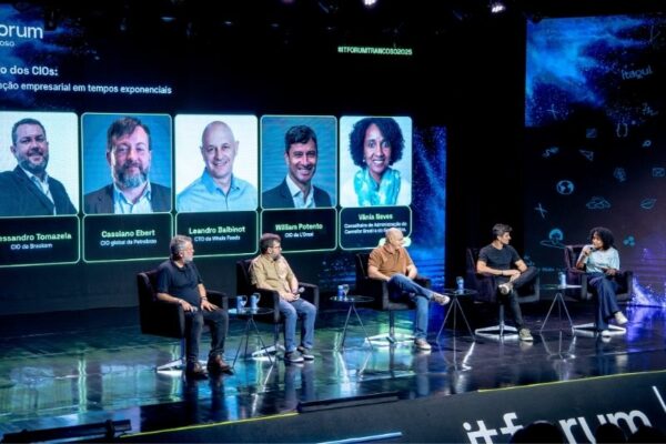 Painel com cinco participantes sentados num palco, todos envolvidos numa discussão sobre tecnologia e liderança empresarial. Atrás deles, um grande ecrã exibe os rostos e cargos de Alessandro Tomazela (CIO da Braskem), Cassiano Ebert (CIO global da Peersoft), Leandro Balbinot (CIO da Whole Foods), William Potento (CIO da Unisul) e Vânia Neves (Consultora de Administração do Carrefour Brasil e do Oi). O ambiente é moderno e iluminado com luzes azuis. No topo direito está a hashtag #ITFORUMTRANCOSO2025.