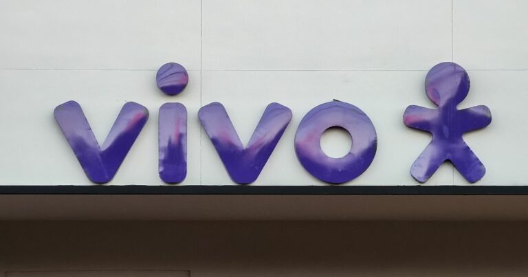 Logótipo da operadora de telecomunicações "Vivo" em letras minúsculas, com tipografia arredondada na cor roxa com reflexos rosados. À direita da palavra, está o símbolo da marca: uma figura humana estilizada com braços e pernas abertas, também em roxo., solução