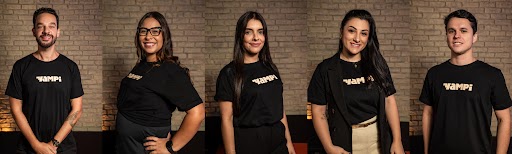 Foto oficial do time da Yampi com cerca de vinte pessoas reunidas, posando sorridentes em ambiente aberto e informal. Todos estão alinhados lado a lado, expressando união e diversidade da equipe.