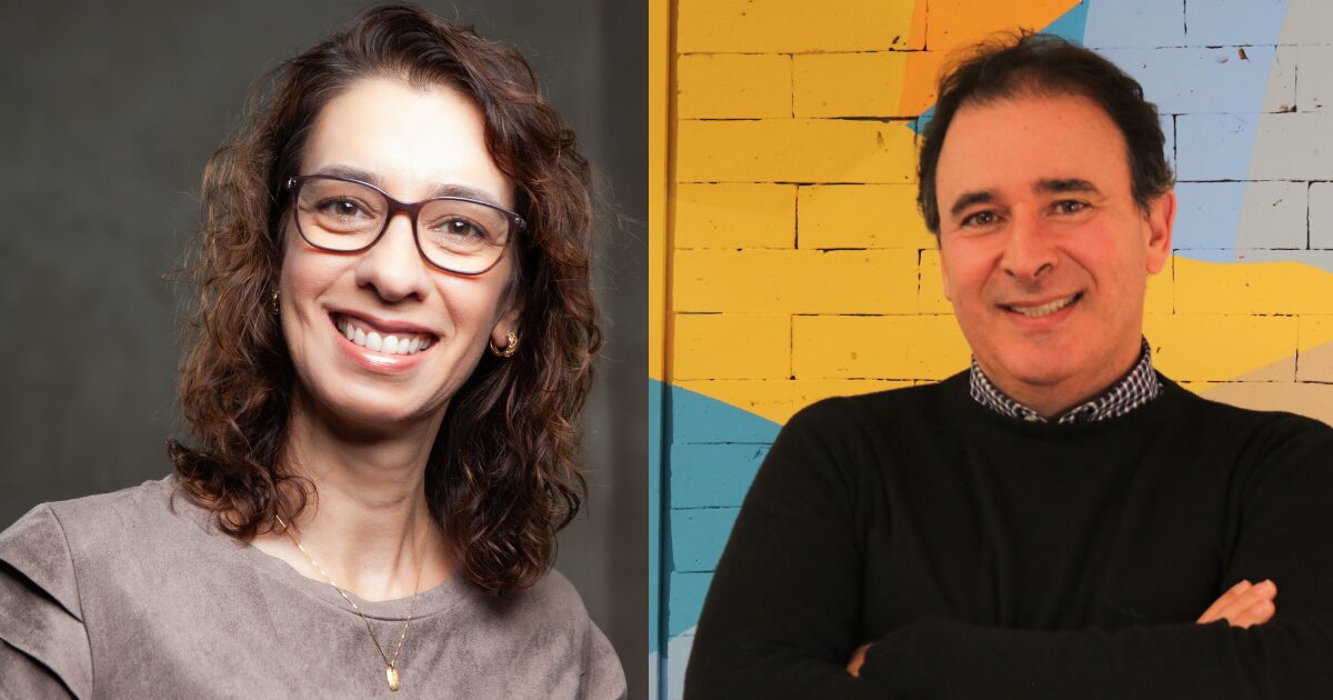 Adriana Valério e Gilberto Rovai Jr.. Adriana aparece à esquerda da imagem, sorrindo, com cabelos castanhos ondulados, óculos de grau e blusa cinza; ao fundo, um cenário neutro. À direita está Gilberto Rovai Jr., também sorrindo, com os braços cruzados, vestindo suéter preto sobre uma camisa xadrez, em frente a uma parede colorida com padrões geométricos em azul, amarelo e laranja.
