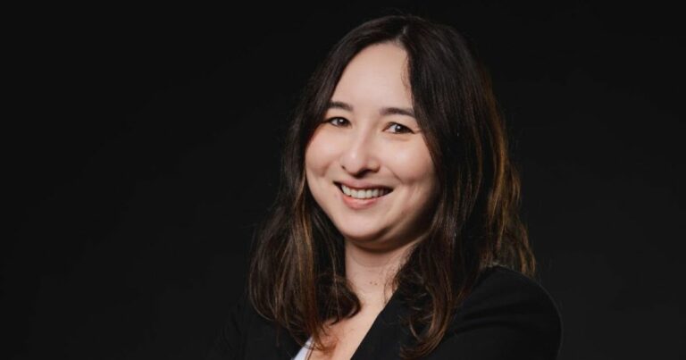 Uma pessoa de cabelos longos, vestindo um blazer de cor escura, está posicionada contra um fundo preto. O rosto da pessoa está desfocado, tornando-a não identificável. (Omni Saúde)