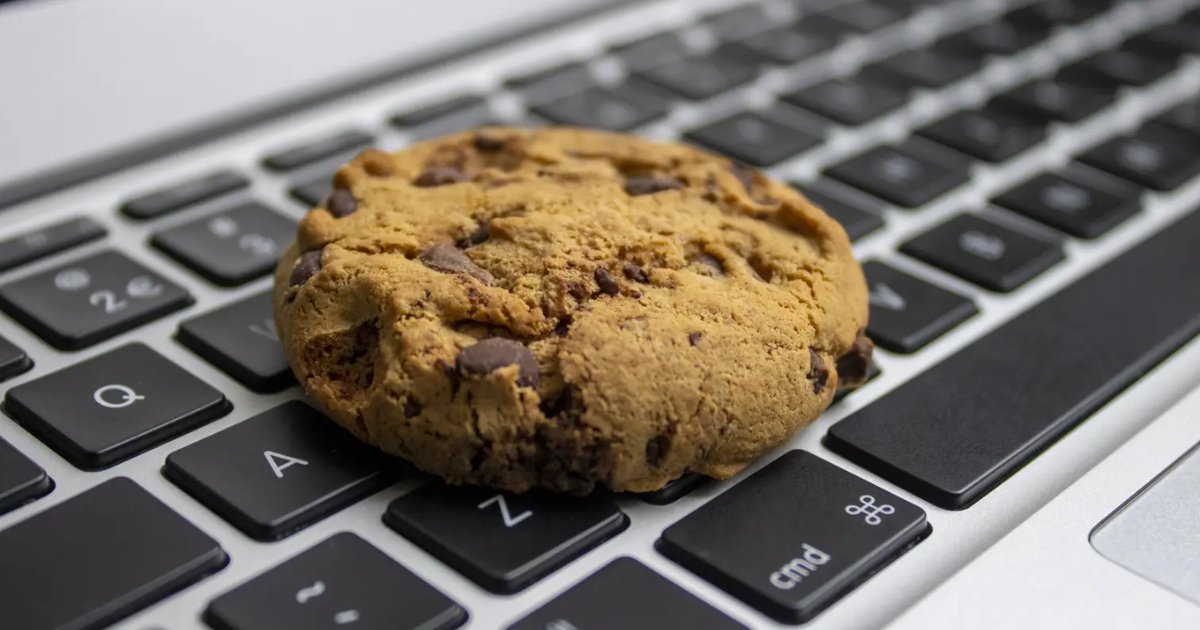 Imagem mostra um cookie de chocolate sobre o teclado de um notebook, especificamente sobre as teclas "A", "Z" e "cmd". A imagem faz uma alusão visual comum ao termo "cookie" utilizado na internet, relacionado a dados armazenados pelo navegador, frequentemente discutidos em contextos de privacidade e vazamento de informações. (cookies)