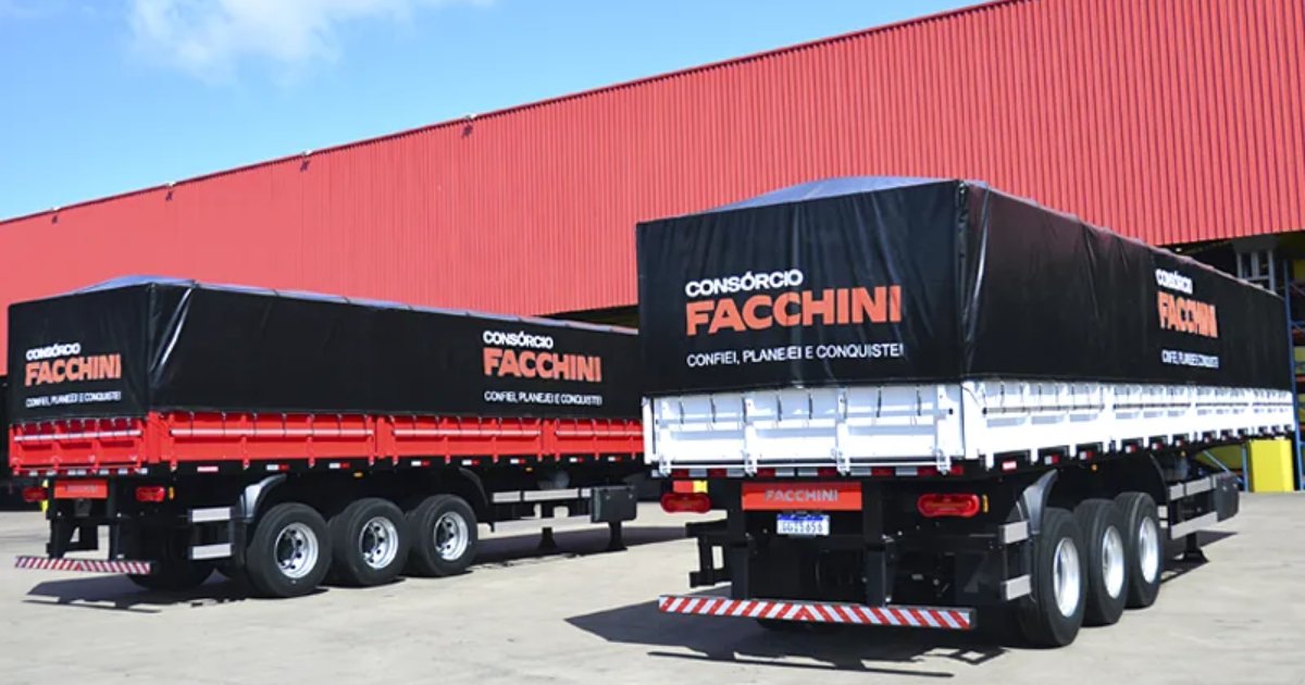 Imagem de dois semirreboques da marca Facchini estacionados em pátio industrial, com lonas pretas que exibem o texto “Consórcio Facchini – Confiei, planejei e conquistei!”. Ao fundo, há um grande galpão vermelho (SAP)